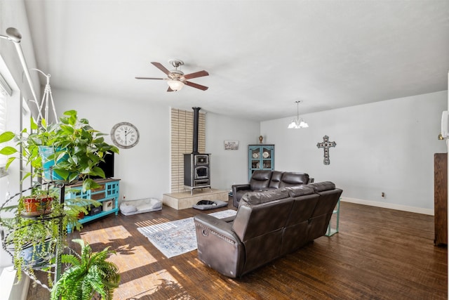 living room with a wood stove, dark hardwood / wood-style floors, and ceiling fan with notable chandelier