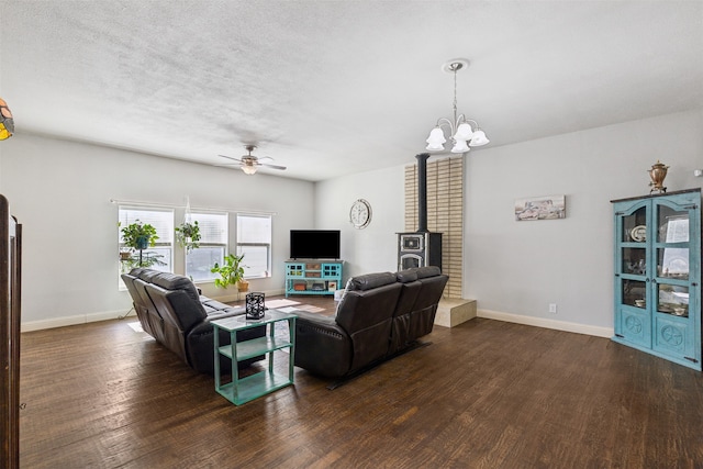 living room with dark hardwood / wood-style flooring, a textured ceiling, a wood stove, and ceiling fan with notable chandelier