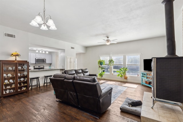 living room featuring hardwood / wood-style floors, a wood stove, and ceiling fan with notable chandelier