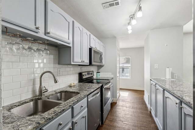 kitchen with a textured ceiling, sink, stone counters, dark hardwood / wood-style floors, and appliances with stainless steel finishes