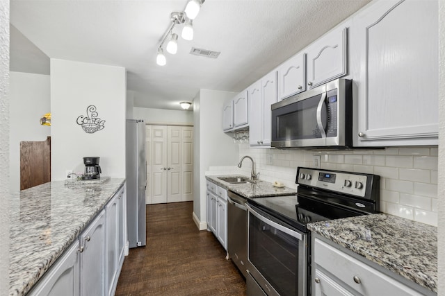 kitchen featuring dark hardwood / wood-style flooring, light stone counters, sink, white cabinetry, and appliances with stainless steel finishes