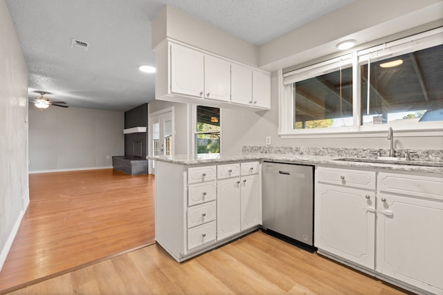 kitchen featuring white cabinets, a textured ceiling, sink, stainless steel dishwasher, and light hardwood / wood-style flooring