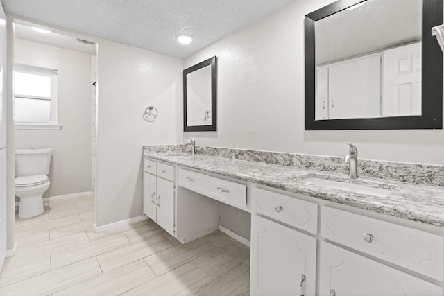 bathroom with vanity, toilet, and a textured ceiling