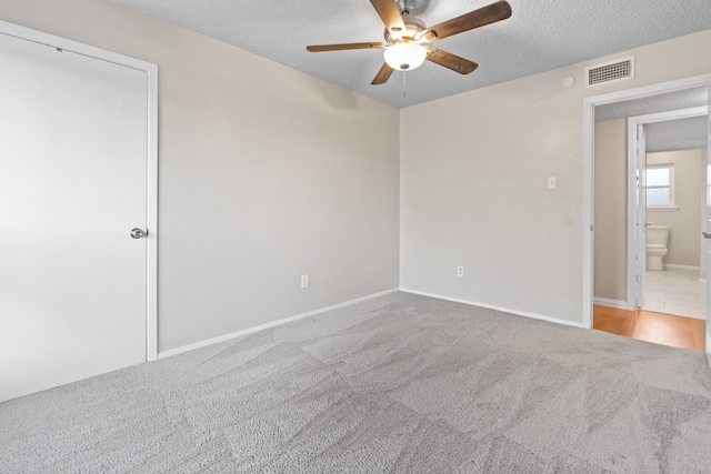 unfurnished room featuring a textured ceiling, carpet floors, and ceiling fan