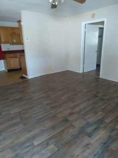 empty room with dark wood-type flooring and ceiling fan