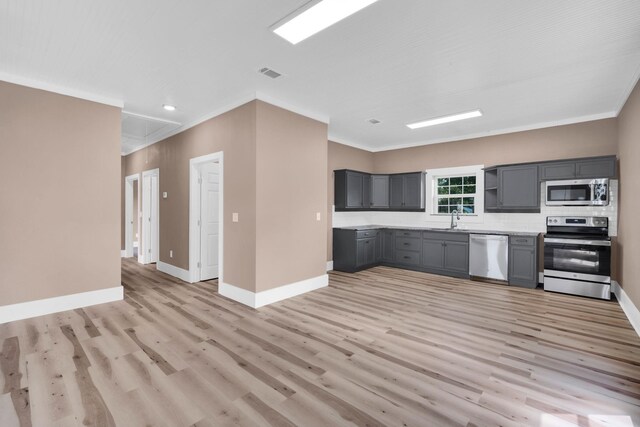 kitchen with stainless steel appliances, sink, ornamental molding, gray cabinets, and light hardwood / wood-style flooring