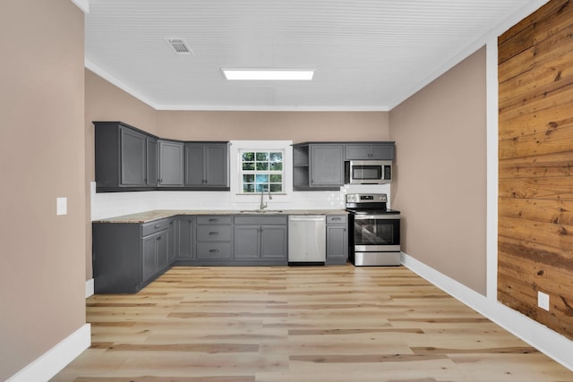 kitchen featuring stainless steel appliances, tasteful backsplash, ornamental molding, gray cabinets, and light hardwood / wood-style flooring