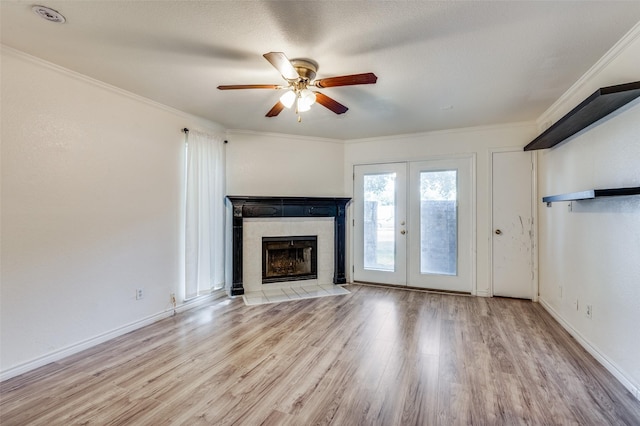 unfurnished living room with baseboards, wood finished floors, crown molding, french doors, and a fireplace