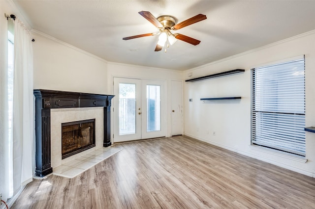 unfurnished living room with ornamental molding, a tile fireplace, french doors, and wood finished floors