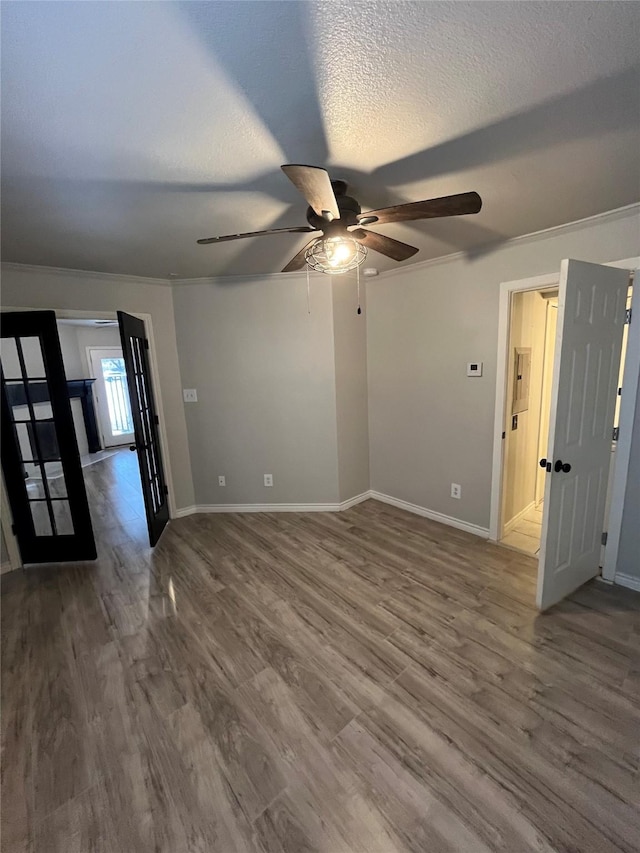 unfurnished room with wood finished floors, a ceiling fan, baseboards, and a textured ceiling