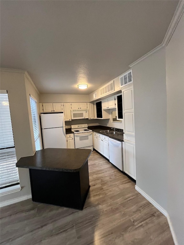 kitchen featuring ornamental molding, dark countertops, dark wood finished floors, white appliances, and baseboards