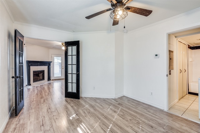 unfurnished living room with a tiled fireplace, french doors, light hardwood / wood-style floors, and crown molding