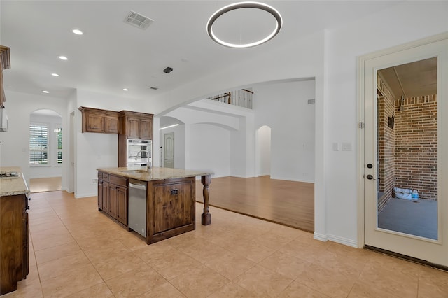 13647 Monstrell Rd, Frisco, TX 75035 - kitchen with a sink, arched walkways, light tile patterned floors, a center island with sink, and recessed lighting
