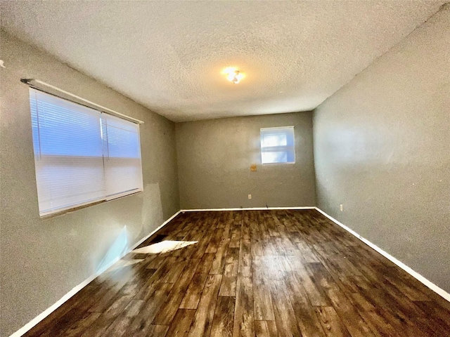 empty room featuring dark wood-type flooring and a textured ceiling