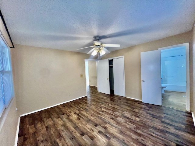 unfurnished bedroom with connected bathroom, a textured ceiling, dark hardwood / wood-style floors, a closet, and ceiling fan