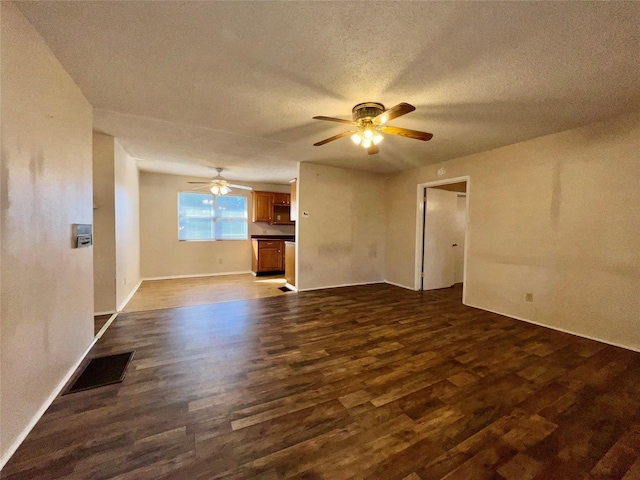 unfurnished living room with ceiling fan, dark wood-type flooring, and a textured ceiling