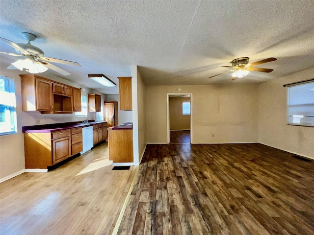 kitchen featuring sink, ceiling fan, dishwasher, a textured ceiling, and light wood-type flooring