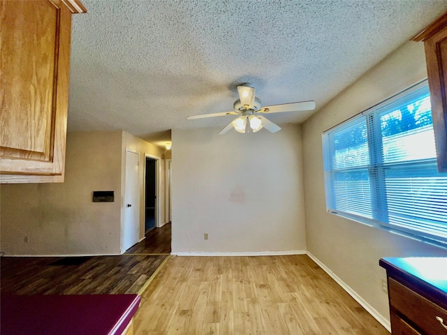 empty room featuring ceiling fan, a textured ceiling, and light wood-type flooring