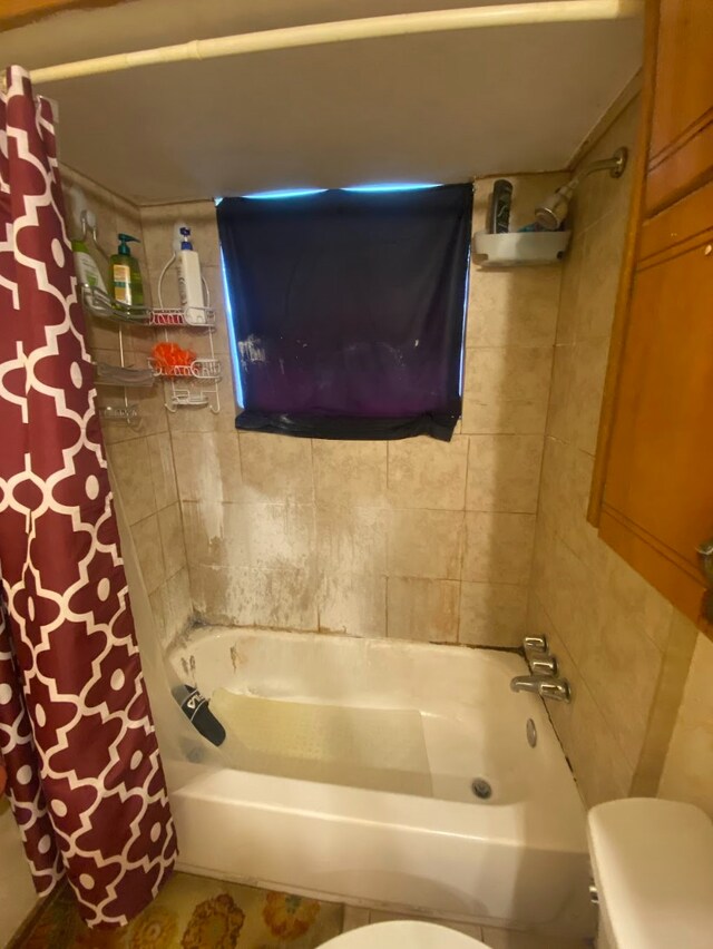 bathroom featuring toilet and shower / bath combination with curtain