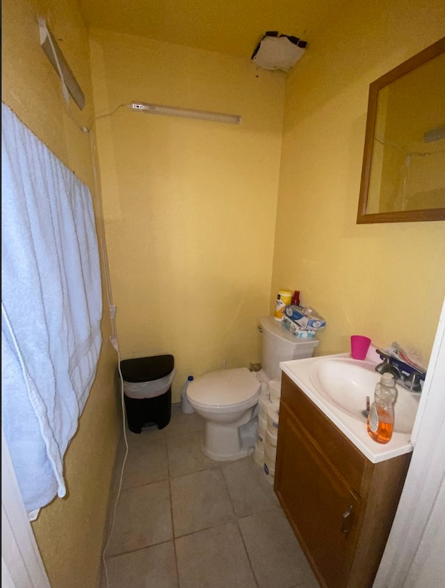 bathroom with toilet, vanity, and tile patterned floors