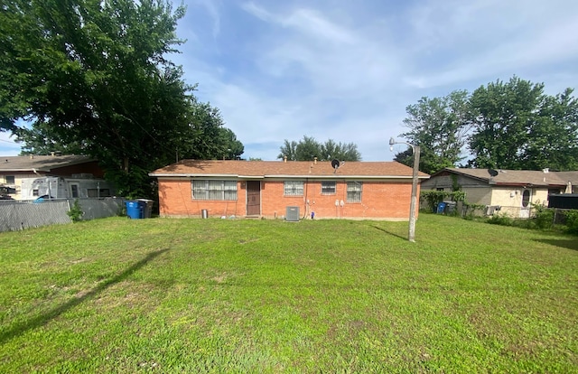 rear view of property featuring central AC unit and a lawn