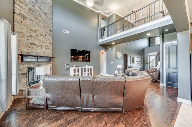 living room with a stone fireplace, a towering ceiling, and hardwood / wood-style floors