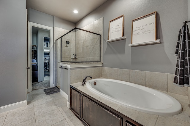 bathroom featuring washer / dryer, tile patterned flooring, and shower with separate bathtub