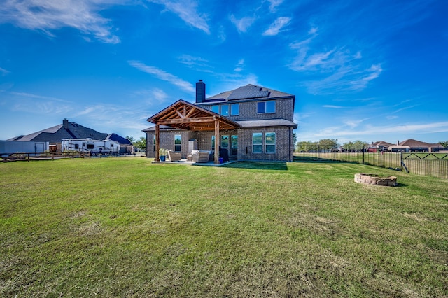 rear view of property featuring a lawn, a patio, and a fire pit