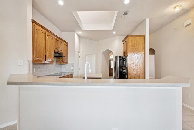 kitchen with black appliances, tasteful backsplash, light tile patterned floors, sink, and kitchen peninsula