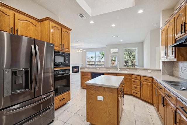 kitchen featuring light tile patterned floors, black appliances, kitchen peninsula, and a center island