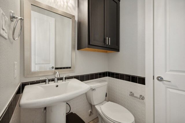 bathroom with tile walls, sink, and toilet