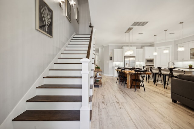 stairs with hardwood / wood-style flooring and crown molding