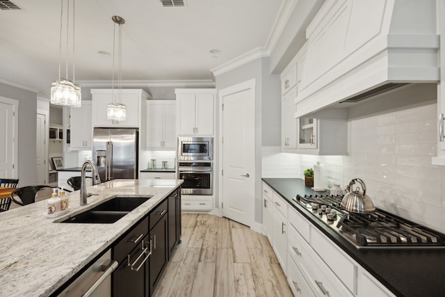 kitchen featuring light hardwood / wood-style floors, hanging light fixtures, sink, white cabinetry, and appliances with stainless steel finishes