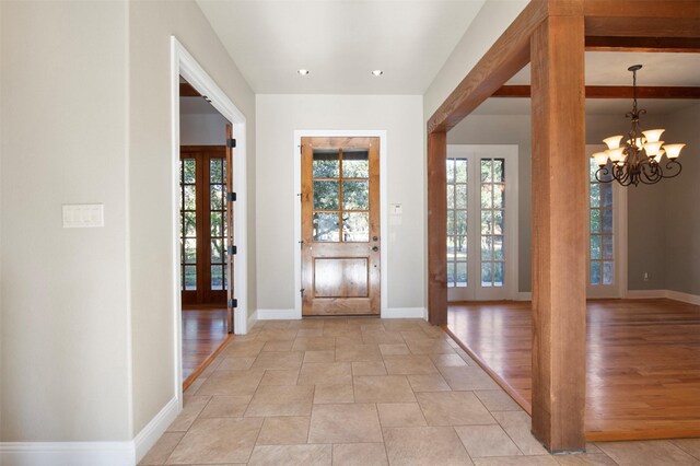 foyer entrance with french doors, light hardwood / wood-style floors, beamed ceiling, and a chandelier