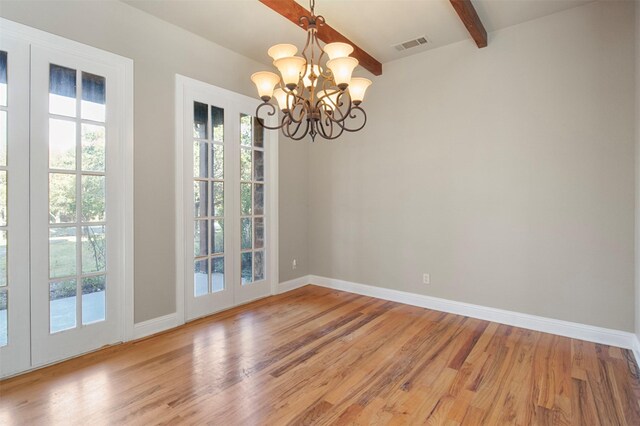 unfurnished dining area featuring hardwood / wood-style floors, a chandelier, and beam ceiling