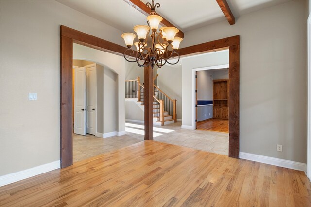 unfurnished dining area featuring light hardwood / wood-style floors, a chandelier, and beam ceiling