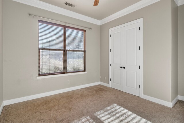 unfurnished bedroom with a closet, carpet flooring, ceiling fan, and crown molding