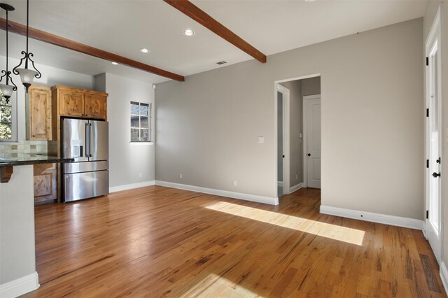 kitchen featuring tasteful backsplash, decorative light fixtures, beam ceiling, high quality fridge, and light hardwood / wood-style flooring