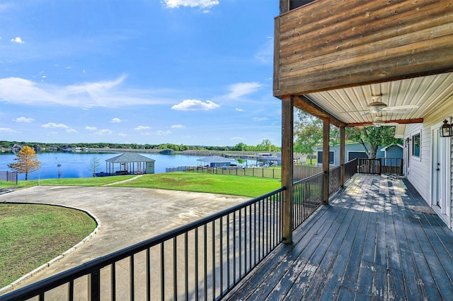 wooden terrace with a lawn, ceiling fan, and a water view