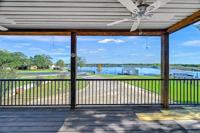 wooden deck featuring a lawn, ceiling fan, and a water view