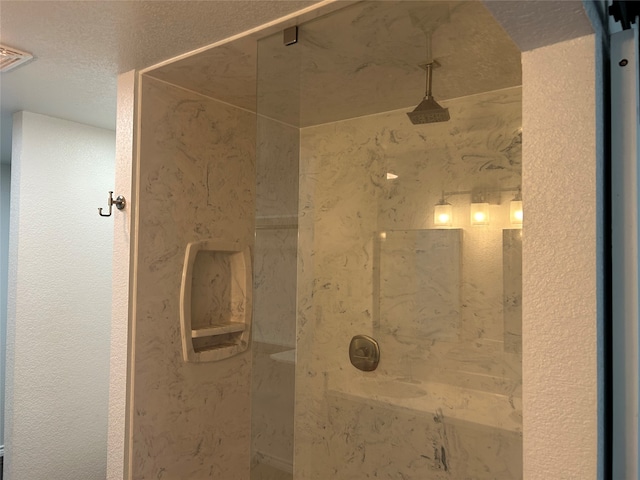 bathroom with a textured ceiling and a tile shower