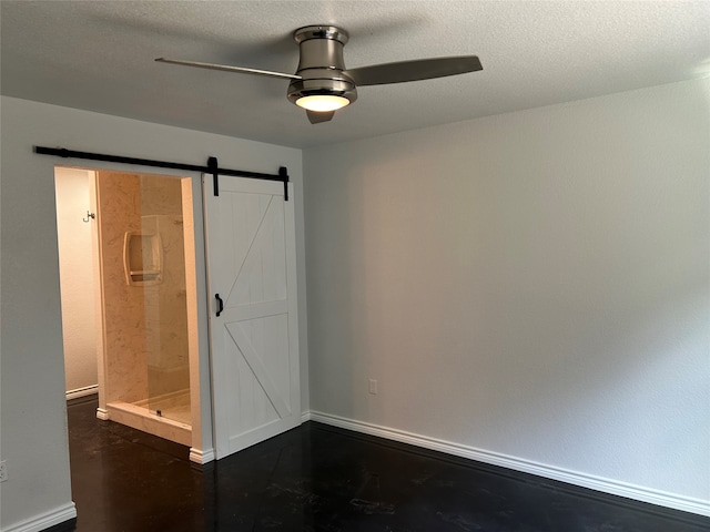 spare room featuring a barn door, ceiling fan, and a textured ceiling