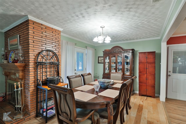 dining area with a textured ceiling, a notable chandelier, light hardwood / wood-style flooring, and ornamental molding