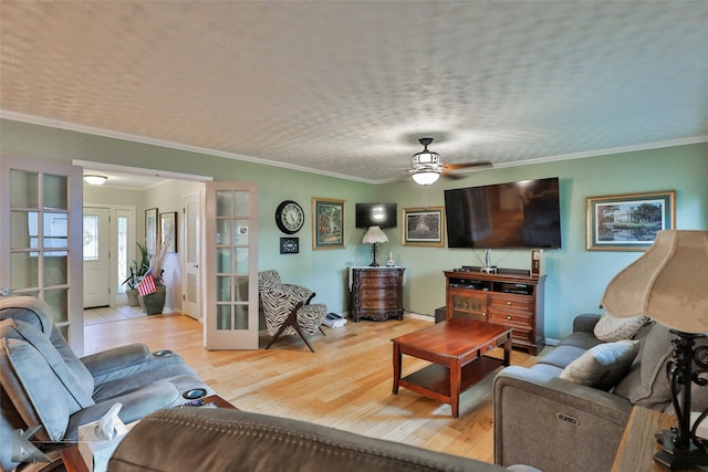 living room with ornamental molding, light wood-type flooring, ceiling fan, and french doors