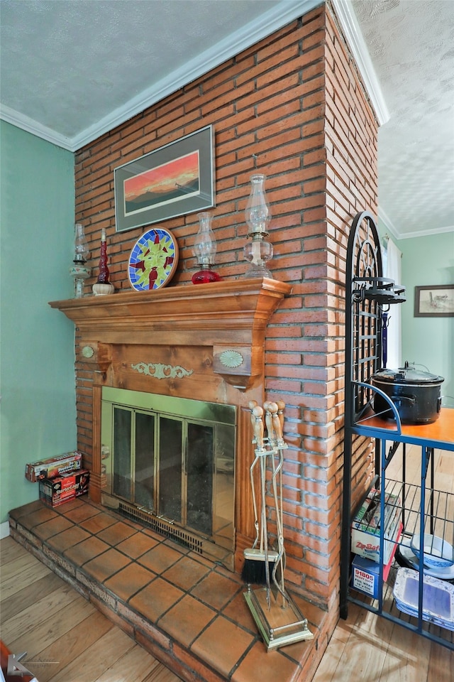 room details featuring a textured ceiling, wood-type flooring, ornamental molding, and a brick fireplace