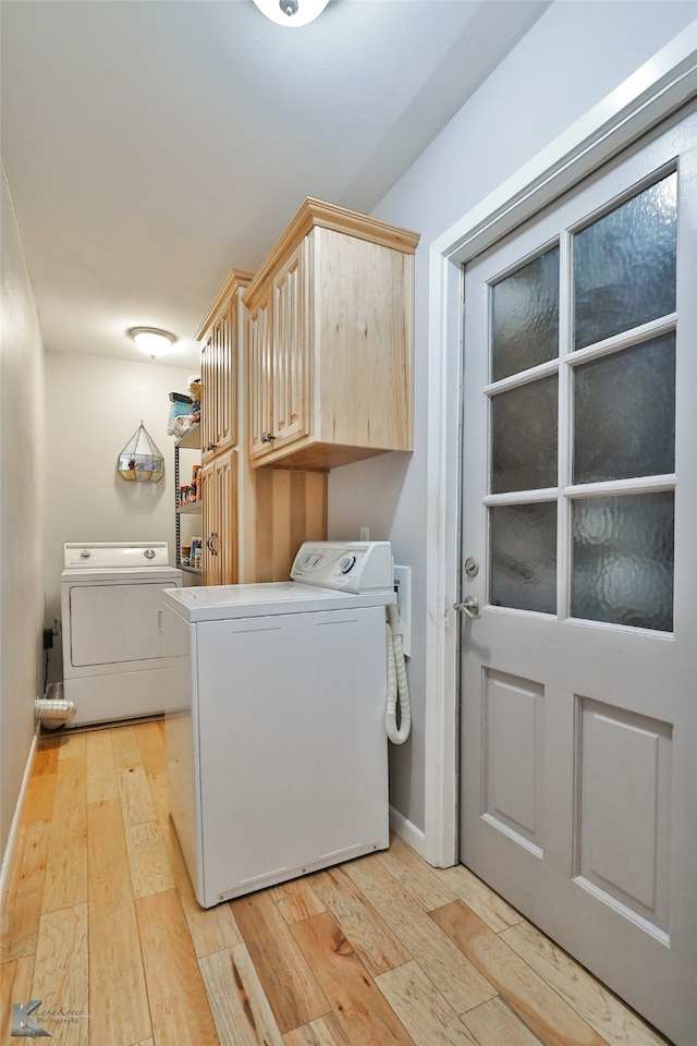 laundry area featuring light wood-type flooring, cabinets, and washer and dryer