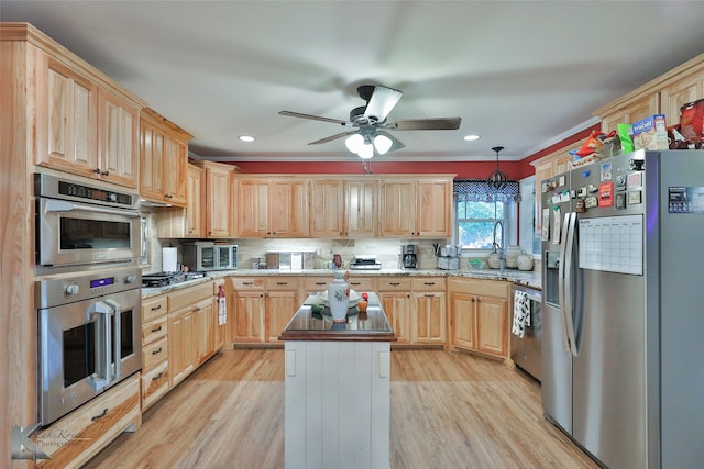 kitchen with ornamental molding, stainless steel appliances, a kitchen island, pendant lighting, and light hardwood / wood-style floors