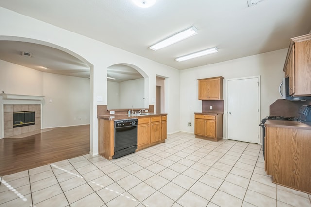 kitchen with dishwasher, a tiled fireplace, sink, and light hardwood / wood-style flooring