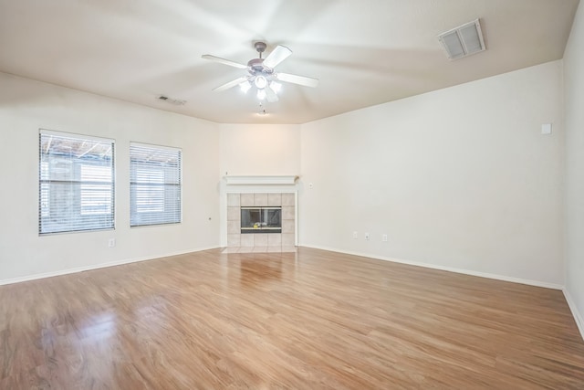 unfurnished living room with light hardwood / wood-style floors, ceiling fan, and a tile fireplace