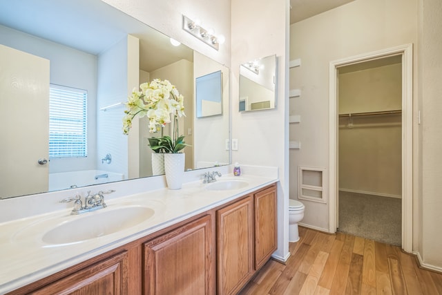 bathroom featuring a bathing tub, vanity, hardwood / wood-style flooring, and toilet